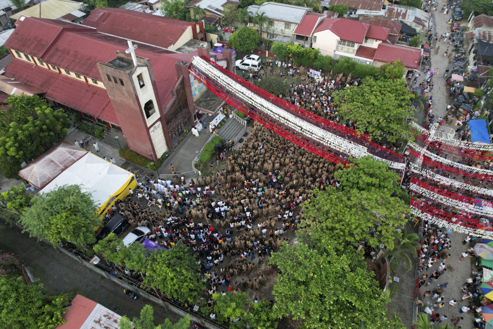 Devout Catholics gather at the church of Saint John the Baptist during the mud festival at Bibiclat, Nueva Ecija province, northern Philippines, Monday, June 24, 2024. (AP Photo/Aaron Favila)