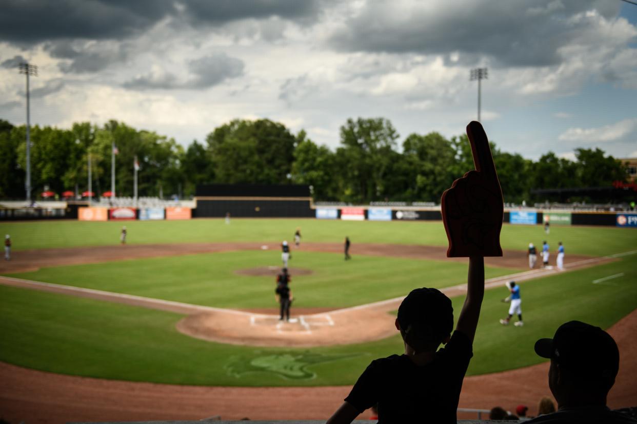 William Durham, 8, holds up his foam finger as he watches the Fayetteville Woodpeckers play the Down East Wood Ducks with his dad, Kevin Durham, at Segra Stadium on Friday, June 11, 2021.