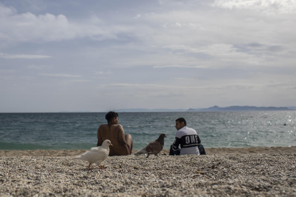 Two men sit at the beach of Alimos, a seaside suburb of Athens, on Friday April 23, 2021. Easter holidays are often celebrated with relatives outside Athens and other cities, but the government has said COVID-19 infection levels remain too high to allow free travel.(AP Photo/Petros Giannakouris)