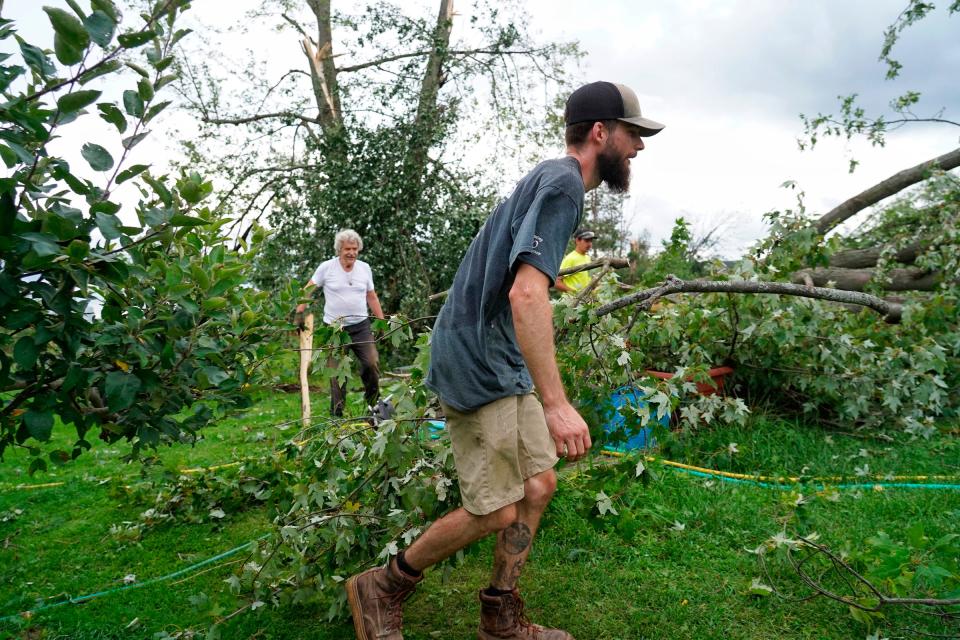 Cody Thompson of Fowlerville helps move branches cut from a fallen tree while helping clear debris in a woman’s yard on Noble Road in Williamston on Friday, August 25, 2023, after a tornado touched down nearby causing damage to the area.