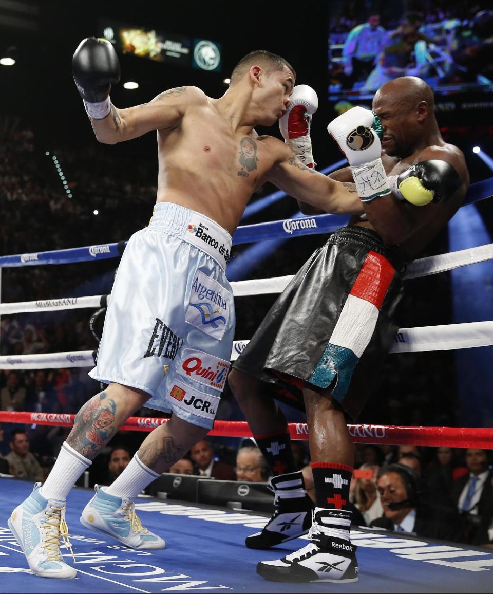 Marcos Maidana, left, from Argentina, drives Floyd Mayweather Jr. against the ropes in their WBC-WBA welterweight title boxing fight Saturday, May 3, 2014, in Las Vegas. (AP Photo/Eric Jamison)