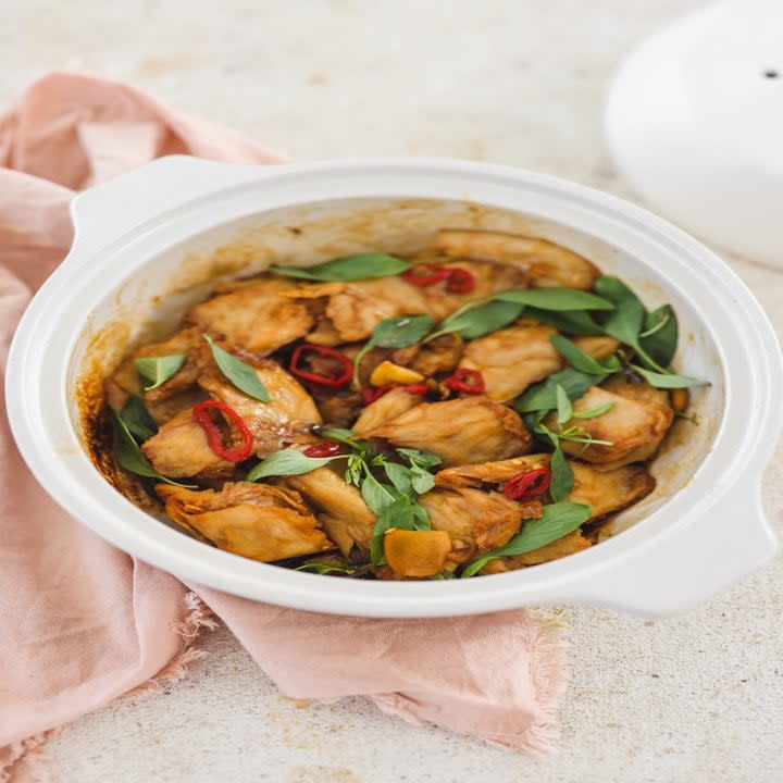 a bowl with chunks of chicken, thai basil, and thai red pepper slices