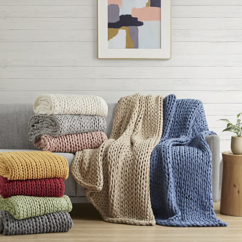 Assorted knit blankets stacked on a chair for home decoration