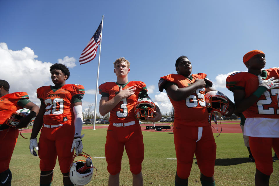 Mosley High football players hold their hands to their heard during the the national anthem, before the start of their football game against Pensacola, in the aftermath of Hurricane Michael in Panama City, Fla., Saturday, Oct. 20, 2018. (AP Photo/Gerald Herbert)