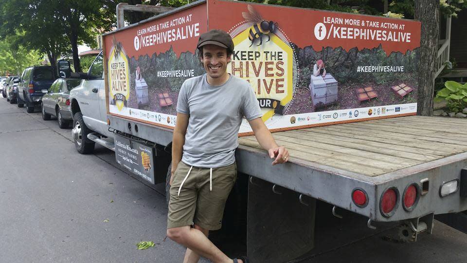 In this June 12, 2016 photo provided by Bird and the Bees Honey, beekeeper James Cook stands in front of a truck in Minneapolis. Cook, now 25, filmed a documentary while driving cross-country to raise awareness about the health of honey bees and the impact of pesticides and other stressors. He ultimately testified before Congress about this. (Bird and the Bees Honey via AP)