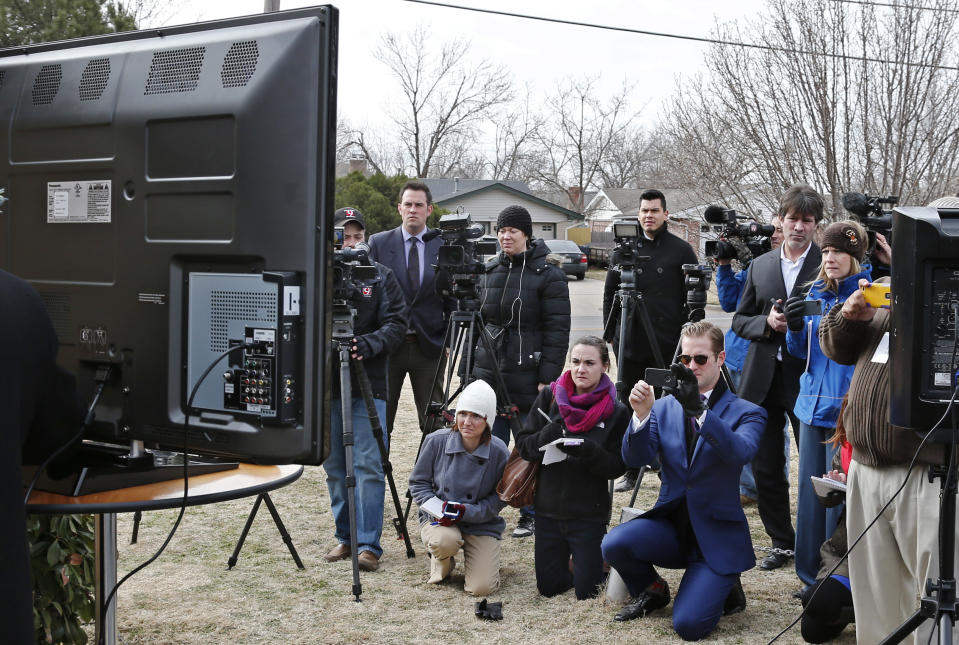 Members of the media watch a video on screen at left during a news conference in Oklahoma City, Tuesday, Feb. 25, 2014. At the news conference, the family of Luis Rodriguez, a man who died after a struggle with police outside an Oklahoma movie theater, released a cellphone video of the incident that shows the man on his stomach on the ground with five officers restraining him, including one officer holding his head down. (AP Photo/Sue Ogrocki)