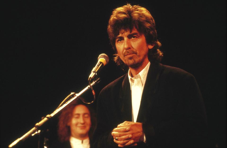 George Harrison with Julian Lennon behind, at The Beatles' induction to the Rock & Roll Hall Of Fame (Photo by Ebet Roberts/Redferns)