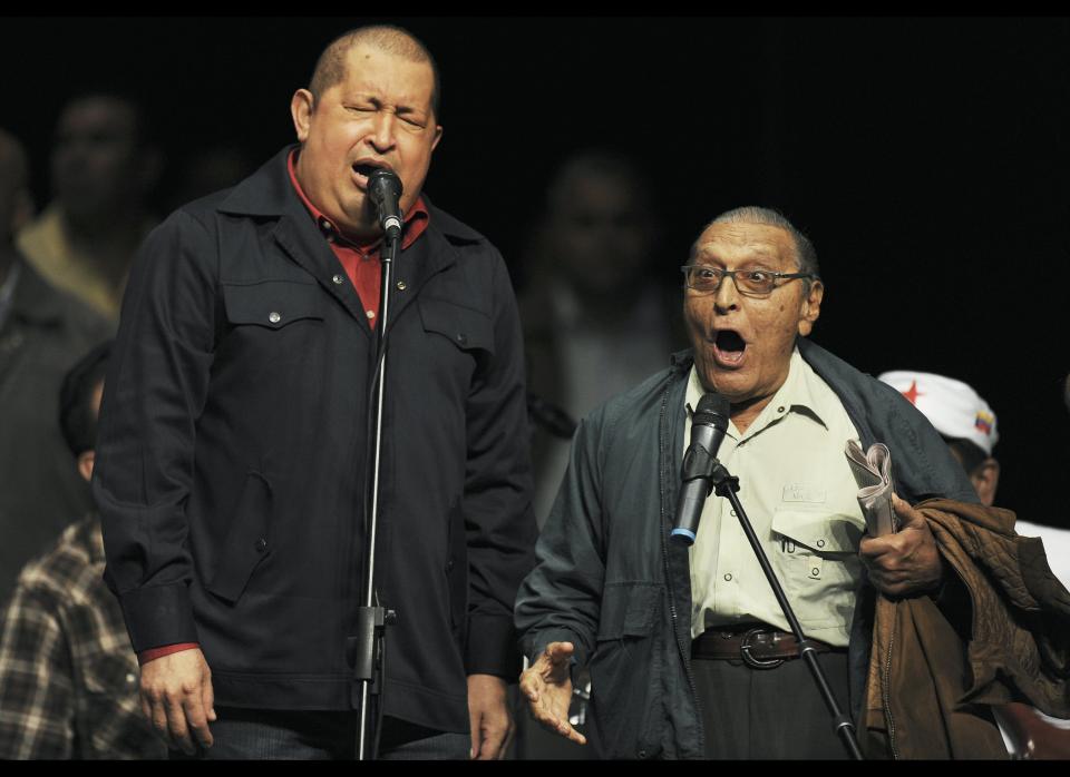 Venezulan President Hugo Chavez (L) sings with an elderly man during the launching of the 'Amor Mayor' programme, which seeks to help senior citizens, in Caracas on December 13, 2011.  AFP PHOTO/Juan BARRETO (Photo credit should read JUAN BARRETO/AFP/Getty Images)