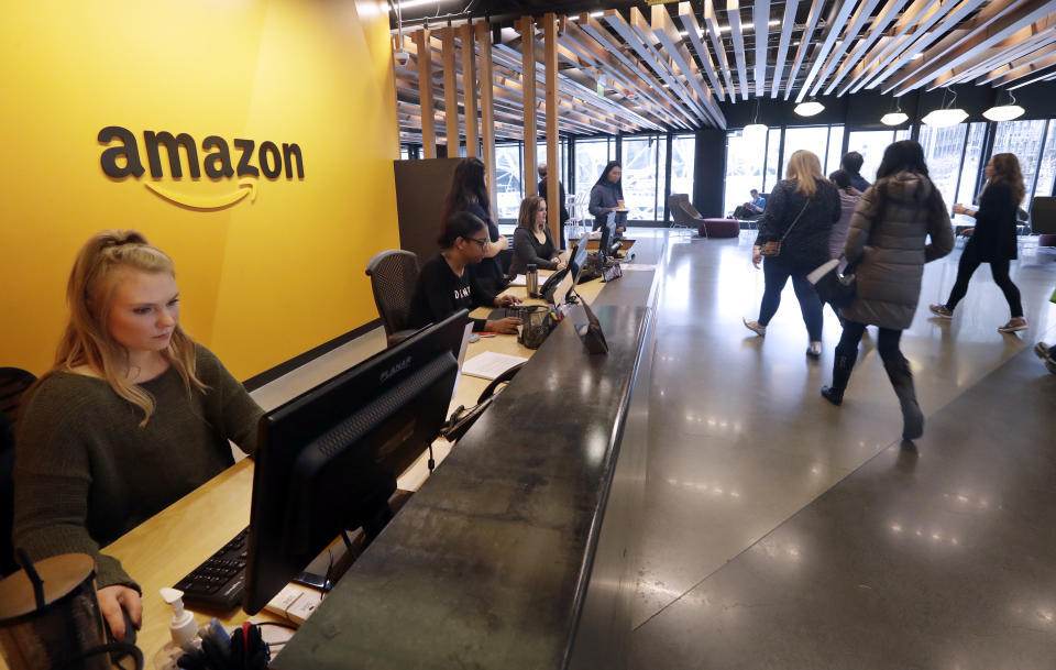 Employees walk through a lobby at Amazon's headquarters Tuesday, Nov. 13, 2018, in Seattle. Amazon, which is growing too big for its Seattle hometown, is spreading out to the East Coast. The online shopping giant ended its 14-month-long competition for a second headquarters Tuesday by selecting New York and Arlington, Va., as the joint winners. (AP Photo/Elaine Thompson)