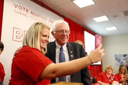 Vermont Senator and U.S. Democratic presidential candidate Bernie Sanders (C) takes a selfie with a supporter during a "Brunch With Bernie" rally at National Nurses United in Oakland, California in this August 10, 2015, file photo. REUTERS/Stephen Lam/Files
