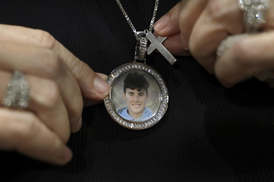 FILE - Gena Hoyer shows the pendant given to her by coworkers bearing a photo of her son, Luke Hoyer, 15, who was killed in the 2018 Marjory Stoneman Douglas High School shootings as well as the cross Luke used to wear around his neck, during a court recess at the Broward County Courthouse in Fort Lauderdale, Fla., Wednesday, Oct. 20, 2021, following shooter Nikolas Cruz's guilty plea on all 17 counts of premeditated murder and 17 counts of attempted murder in the 2018 massacre. (Amy Beth Bennett/South Florida Sun Sentinel via AP, Pool, File)