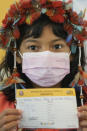 Nine-year-old Indigenous youth Stella Para Poty Fernandes Martins shows her COVID-19 vaccination card to the press after getting a shot of the Pfizer vaccine during a vaccination campaign for children at the Hospital da Clinicas in Sao Paulo, Brazil, Friday, Jan. 14, 2022. The state of Sao Paulo started the COVID-19 vaccination of children between ages 5 and 11. (AP Photo/Andre Penner)