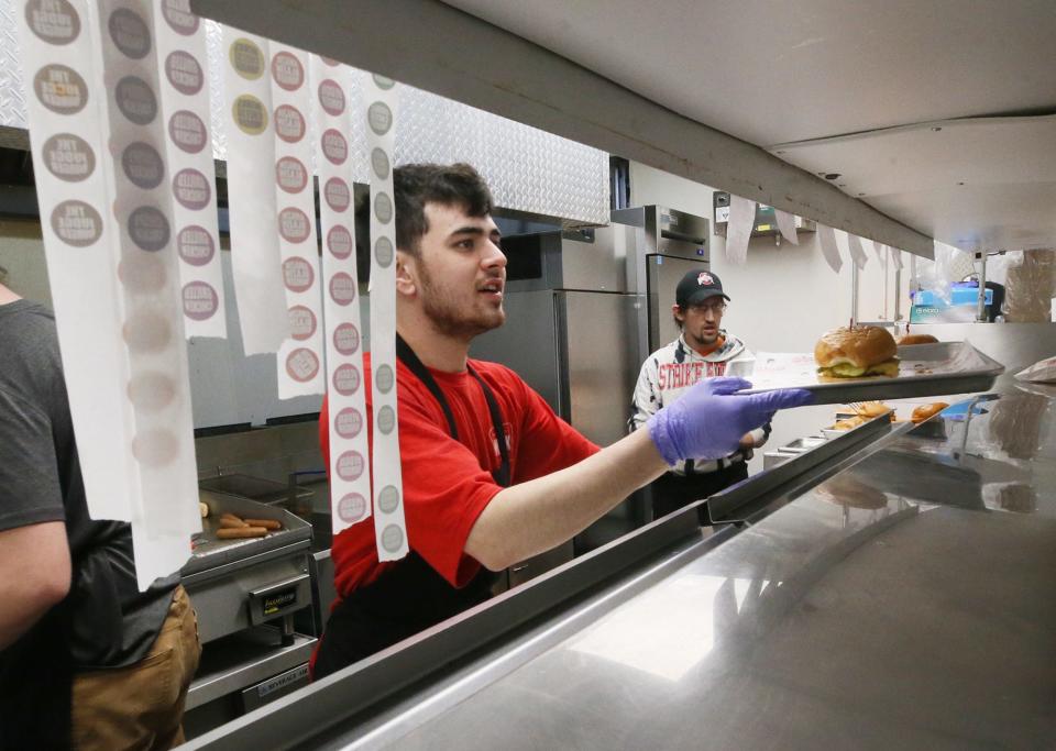 Dylan Pierce puts a completed order up in the kitchen at Wink's Drive-In in Barberton last week.