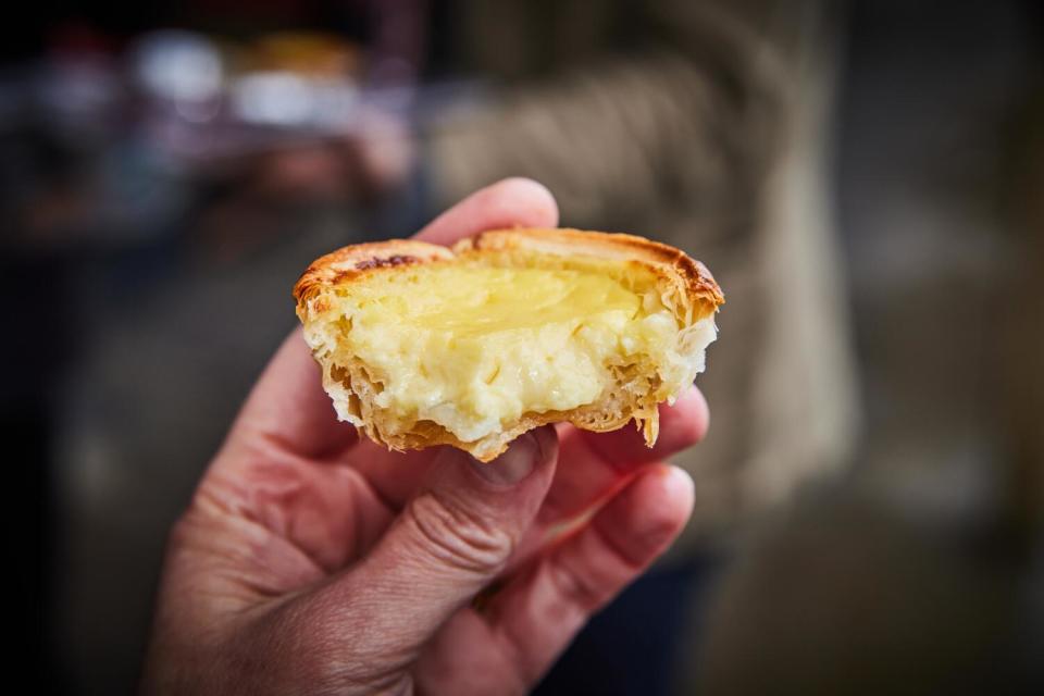 A hand hold up an egg tart from Kee Wah Bakery.