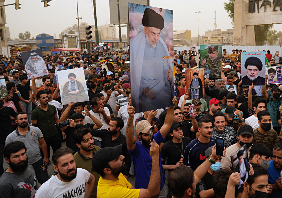 Followers of Shiite cleric Muqtada al-Sadr hold posters with his photo as they celebrate the passing of a law criminalizing the normalization of ties with Israel, in Tahrir Square, Baghdad, Iraq, Thursday, May 26, 2022. (AP Photo/Hadi Mizban)