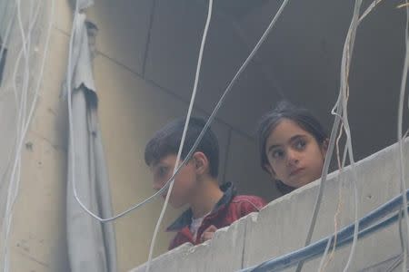 Children look out from a balcony at a site hit by airstrikes, in the rebel-held area of Aleppo's Bustan al-Qasr, Syria April 29, 2016. REUTERS/Abdalrhman Ismail