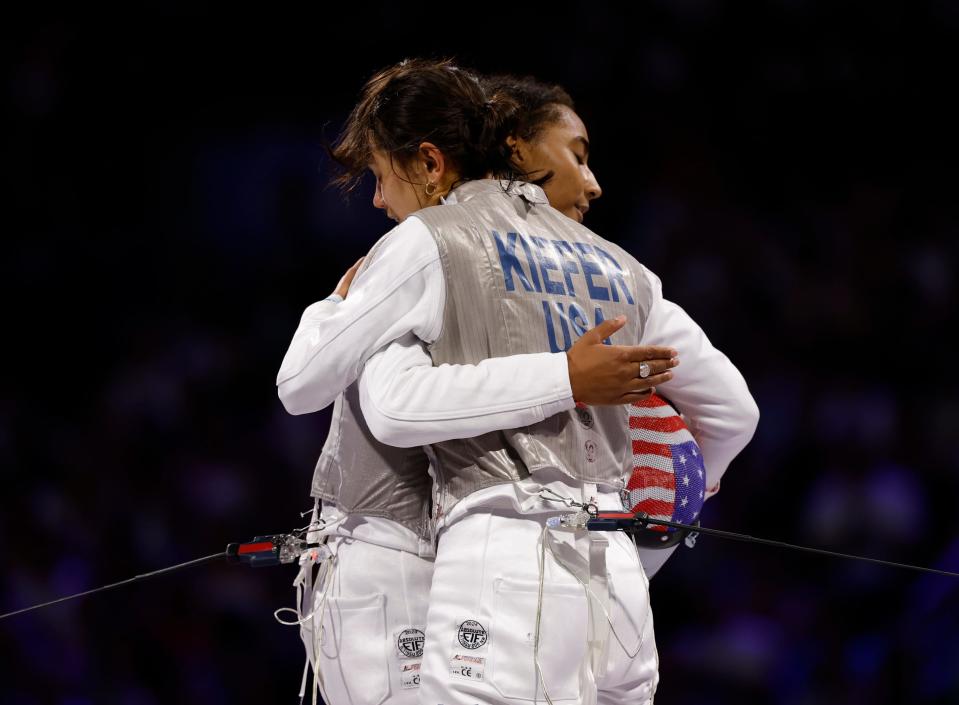 Lee Kiefer and Lauren Scruggs hug after a women's foil gold medal bout during the Paris Olympics.