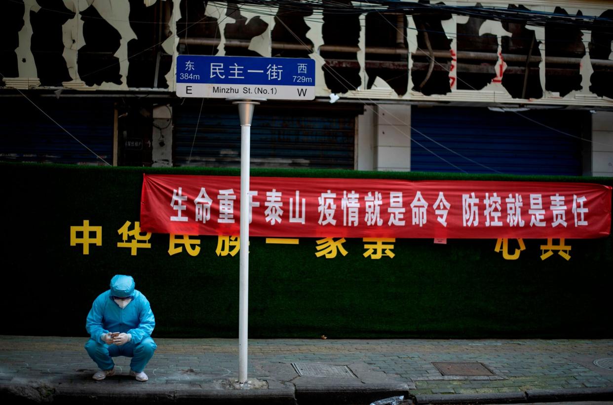 A man wearing personal protective gear uses his phone in Wuhan on Tuesday: AFP/Getty