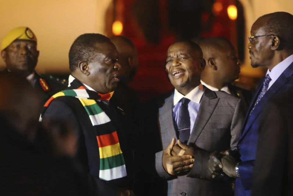 Zimbabwean President Emmerson Mnangagwa, left, arrives at Robert Mugabe International Airport in Harare, Zimbabwe, Monday, Jan. 21, 2019. Mnangagwa arrived in Harare late Monday after cutting short his fund-raising trip in order to address the country's economic crisis and crackdown. (AP Photo/Tsvangirayi Mukwazhi)