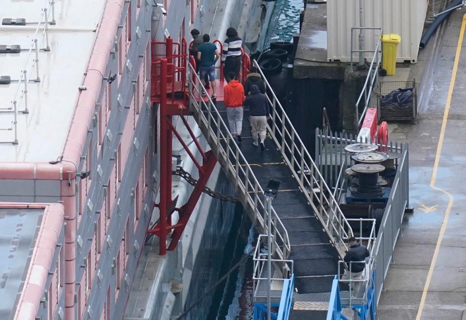 People walk on to the Bibby Stockholm migrant accommodation barge following the death of an asylum seeker on board. (PA)