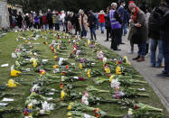 People view flower tributes at Cambridge Gate, at Windsor Castle, one day after the death of Britain's Prince Philip, in Windsor, England, Saturday, April 10, 2021. Britain's Prince Philip, the irascible and tough-minded husband of Queen Elizabeth II who spent more than seven decades supporting his wife in a role that mostly defined his life, died on Friday. (AP Photo/Frank Augstein)