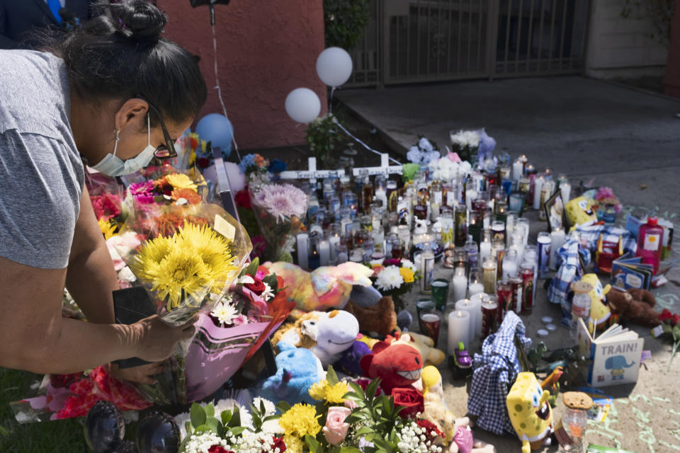 A woman leaves flowers at a memorial for three children who were killed at the Royal Villa apartments complex in the Reseda section of Los Angeles, on Monday, April 12, 2021. Authorities have identified 3-year-old Joanna Denton Carrillo, her 2-year-old brother, Terry, and 6-month-old sister, Sierra, as the three young children who were killed over the weekend. Their mother is the suspect in their deaths and was being held in a central California jail. (AP Photo/Richard Vogel)