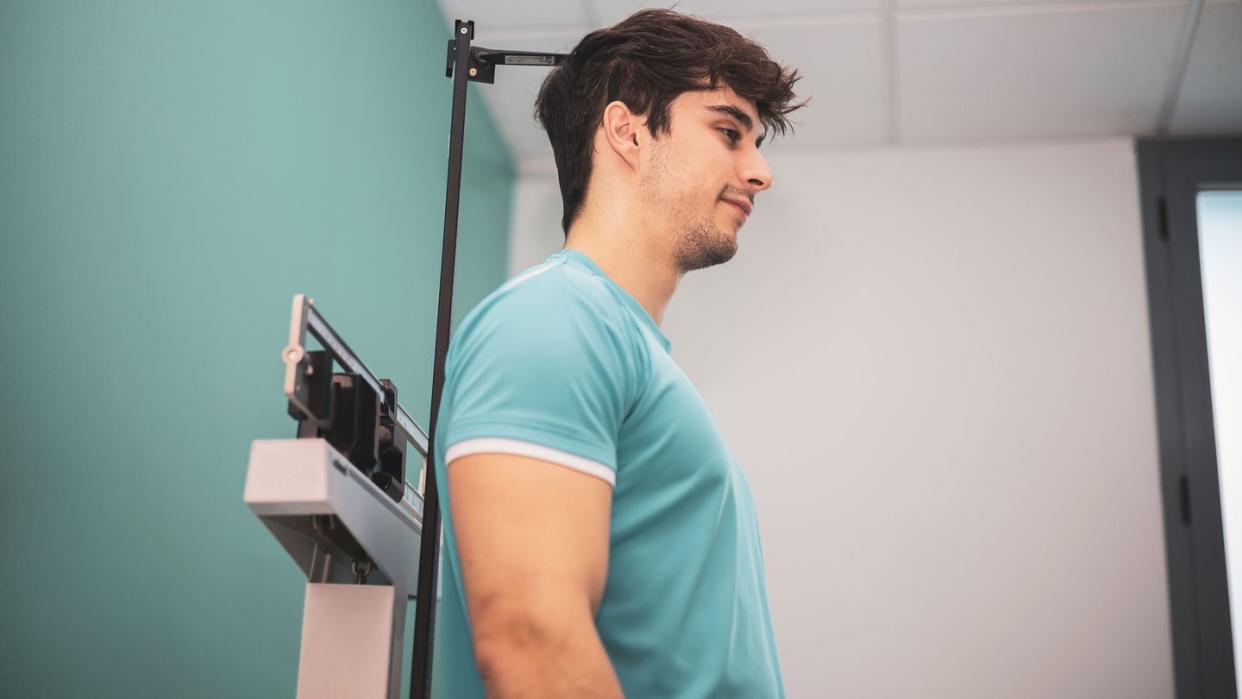 man getting height measured on a doctors office scale