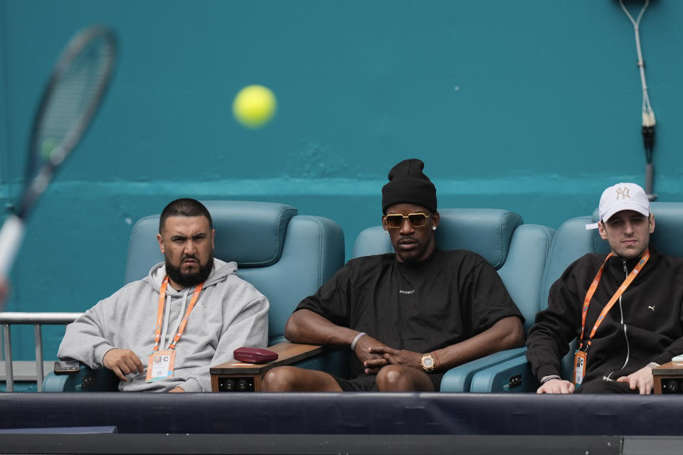 DJ Khaled, left, and Miami Heat forward Jimmy Butler, second left, watch as Alexander Zverev, of Germany, serves to Christopher Eubanks in their men's third round match at the Miami Open tennis tournament, Monday, March 25, 2024, in Miami Gardens, Fla. (AP Photo/Rebecca Blackwell)