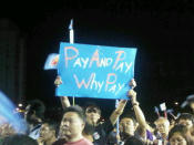 A Workers' Party supporter holding a banner mocking the PAP. (Yahoo! photo/ Fann Sim)