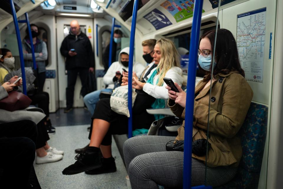 Commuters, most wearing masks because of the coronavirus pandemic, travel on a London Underground