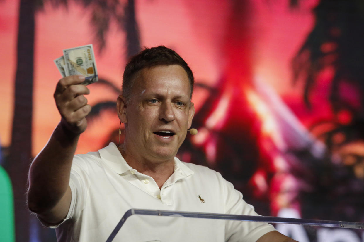 MIAMI, FLORIDA - APRIL 7:  Peter Thiel, co-founder of PayPal, Palantir Technologies, and Founders Fund, holds hundred dollar bills as he speaks during the Bitcoin 2022 Conference at Miami Beach Convention Center on April 7, 2022 in Miami, Florida. The worlds largest bitcoin conference runs from April 6-9, expecting over 30,000 people in attendance and over 7 million live stream viewers worldwide.(Photo by Marco Bello/Getty Images)