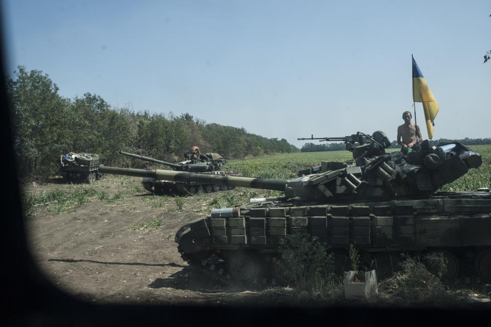 FILE - Ukrainian army tanks take their positions near Illovaisk, Donetsk region, eastern Ukraine, Aug. 14, 2014. A peace agreement for eastern Ukraine has remained stalled for years, but it has come into the spotlight again amid a Russian military buildup near Ukraine that has fueled invasion fears. On Thursday, Feb. 10, 2022 presidential advisers from Russia, Ukraine, France and Germany are set to meet in Berlin to discuss ways of implementing the deal that was signed in the Belarusian capital of Minsk in 2015. (AP Photo/Evgeniy Maloletka, file)
