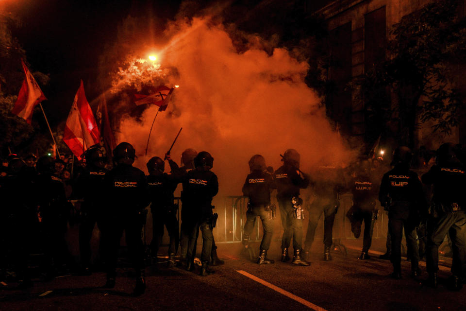 Police charge against far-right protesters as smoke flares are set off outside the Spanish Socialist party headquarters in Madrid, Spain, Monday Nov. 6, 2023. Three people have been arrested late on Monday in a protest against negotiations between Spain's acting government and Catalan separatist parties over a possible amnesty for thousands involved in Catalonia's independence movement. (Ricardo Rubio/Europa Press via AP)