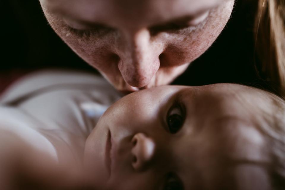 mother kissing her thoughtful baby girl who is looking at the camera