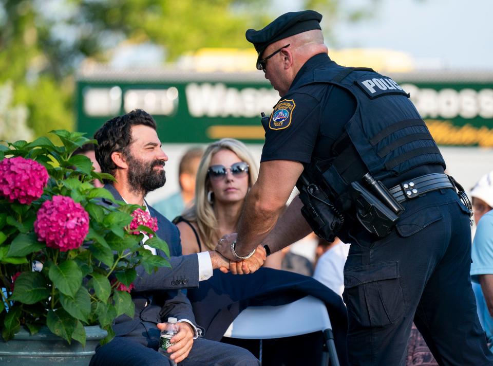 Jim Sheils, Katie Seley's fiance, shaking hands with Upper Makefield police Officer Harry Vitello at the vigil honoring both victims and survivors of the recent flash flooding in Upper Makefield at the 911 Memorial Garden of Reflection in Yardley on Sunday, July 23, 2023.