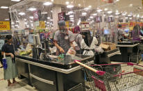 Cashiers serve customers from behind a plastic sheet barriers installed as a precaution against the new coronavirus outbreak, at the supermarket at AEON shopping mall in Tangerang, on the outskirts of Jakarta, Indonesia, Friday, May 22, 2020. Indonesia has seen a surge in coronavirus infections ahead of this this weekend's celebrations marking the end of Ramadan, raising questions about the commitment to the virus fight from both the government and the public. (AP Photo/Tatan Syuflana)