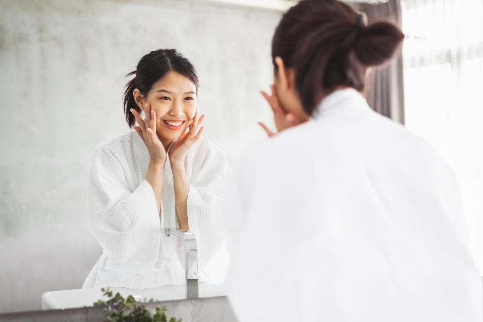 A woman applying moisturiser followed by retinol. (Photo: Getty Images)