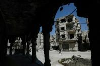 Syrians walk past damaged buildings in the rebel-held town of Douma, on the eastern outskirts of Damascus, on April 7, 2017