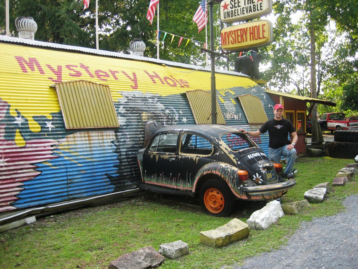 Man posing in front of the Mystery Hole building.