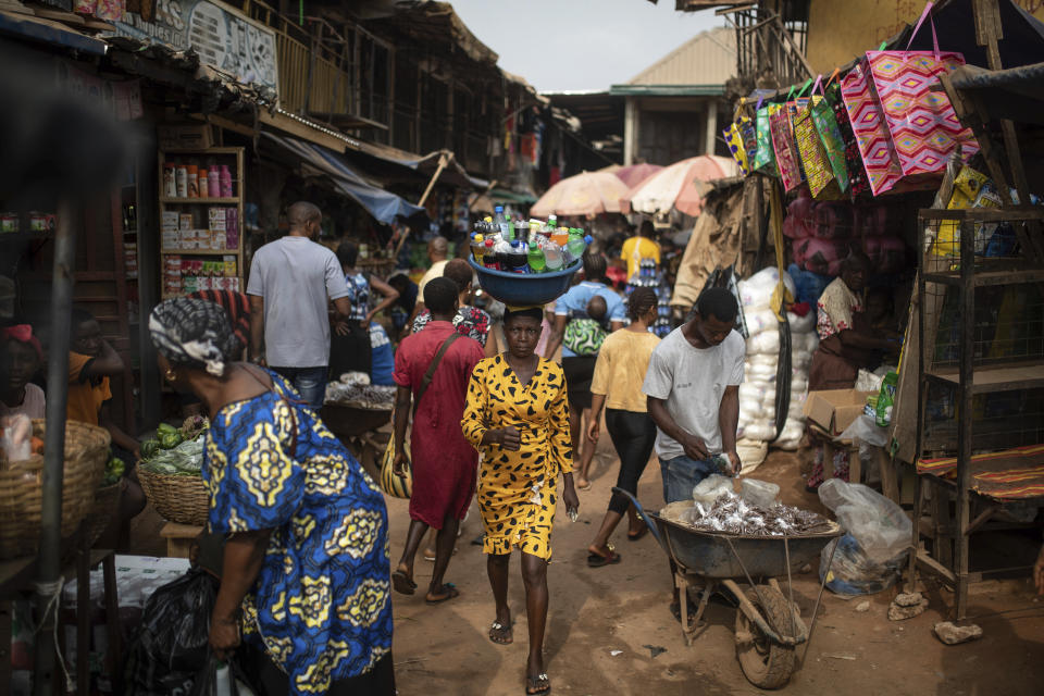 People walk in a local market as vendors and shop-owners display their goods, in Anambra, Nigeria, Friday, Feb. 24, 2023. Nigerian voters are heading to the polls Saturday to select a new president following the second and final term of incumbent President Muhammadu Buhari. (AP Photo/Mosa'ab Elshamy)