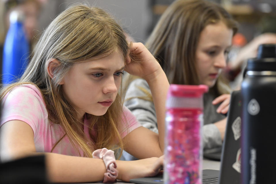 Olivia Laski, left, and Annabelle Harwood attempt to "Find the Bot" in Donnie Piercey's class at Stonewall Elementary in Lexington, Ky., Monday, Feb. 6, 2023. Students in the class each summarized a text about boxing champion and Kentucky icon Muhammad Ali then tried to figure out which summaries were penned by classmates and which was written by the chatbot. The chatbot was the new artificial intelligence tool, ChatGPT, which can generate everything from essays and haikus to term papers in a matter of seconds. (AP Photo/Timothy D. Easley)