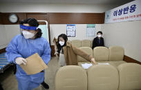 Nursing home workers take a seat after receiving the first dose of the AstraZeneca COVID-19 vaccine at a health care center in Seoul Friday, Feb. 26, 2021. South Korea on Friday administered its first available shots of coronavirus vaccines to people at long-term care facilities, launching a mass immunization campaign that health authorities hope will restore some level of normalcy by the end of the year. (Jung Yeon-je /Pool Photo via AP)