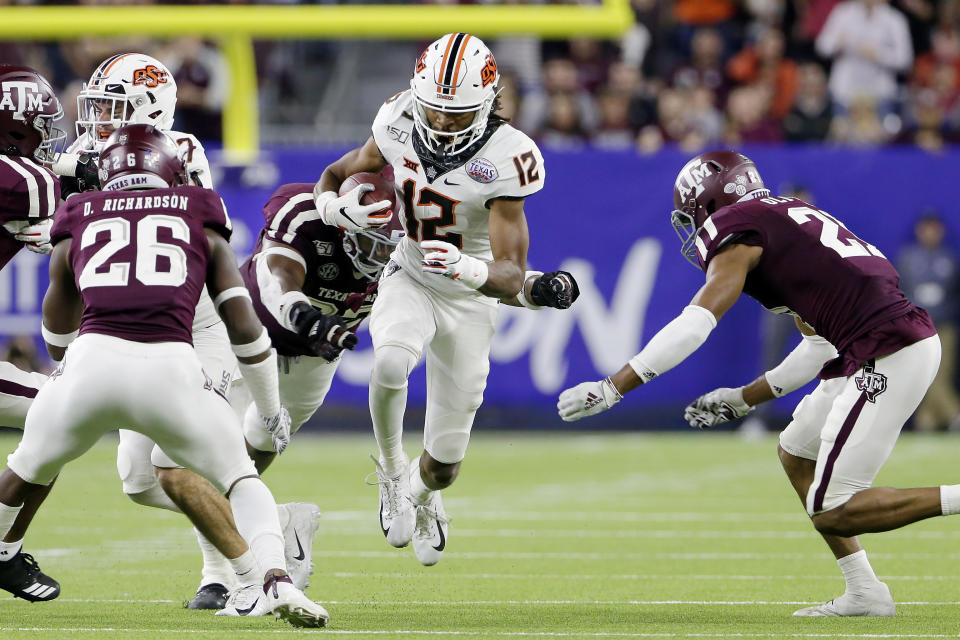 Oklahoma State wide receiver Jordan McCray (12) tries to make it through Texas A&M defenders, from left, Demani Richardson (26), Jayden Peevy, back, and Charles Oliver (21) during the second half of the Texas Bowl NCAA college football game Friday, Dec. 27, 2019, in Houston. (AP Photo/Michael Wyke)