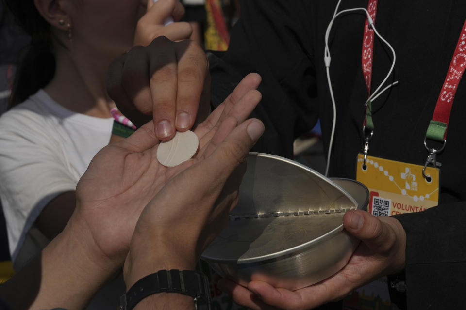 Pilgrims receive the Holy Communion at Parque Tejo in Lisbon where Pope Francis is presiding over a mass celebrating the 37th World Youth Day, Sunday, Aug. 6, 2023. An estimated 1.5 million young people filled the parque on Saturday for Pope Francis' World Youth Day vigil, braving scorching heat to secure a spot for the evening prayer and to camp out overnight for his final farewell Mass on Sunday morning. (AP Photo/Ana Brigida)