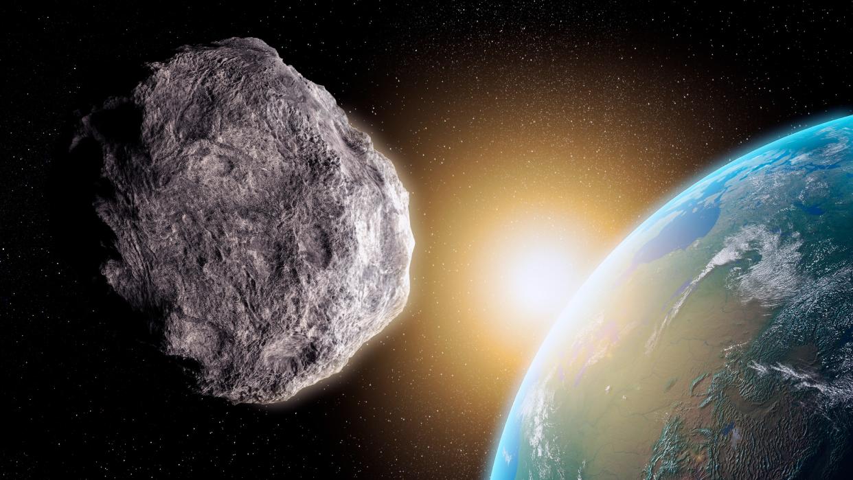  An illustration of a large, round asteroid having a close encounter with the blue Earth. 