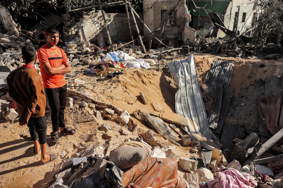 Children stand by an impact crater at the site of a building that was hit by Israeli bombardment in Rafah in the southern Gaza Strip on 8 May 2024 (AFP via Getty Images)