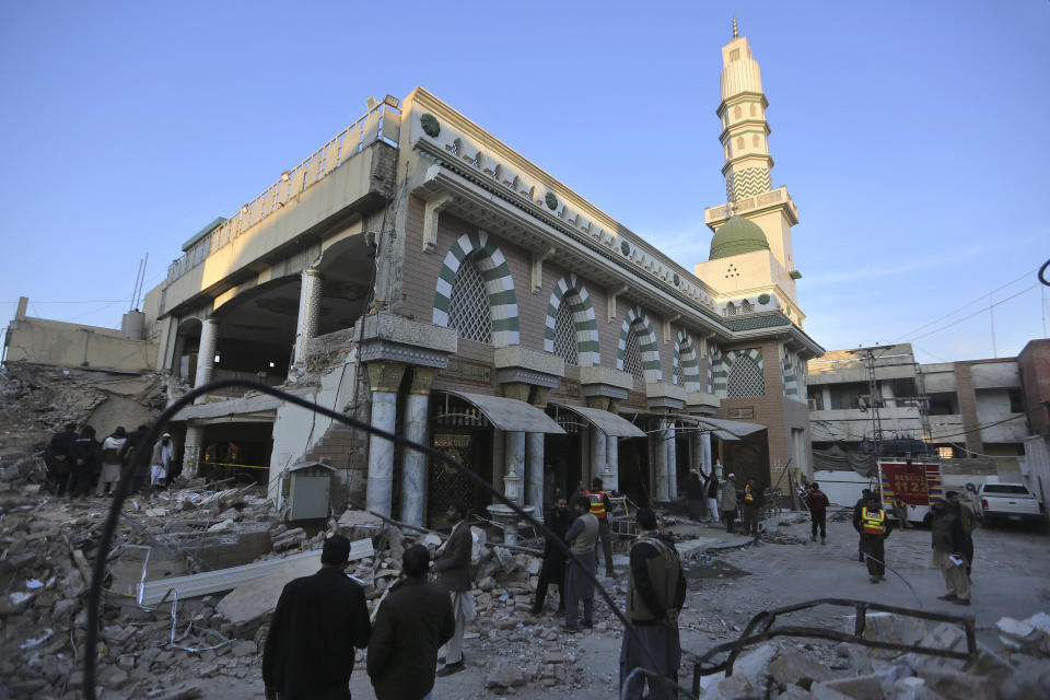 Varias personas observan el exterior de una mezquita donde la víspera hubo un atentado suicida con explosivos, en Peshawar, Pakistán, el martes 31 de enero de 2023. (AP Foto/Muhammad Sajjad)