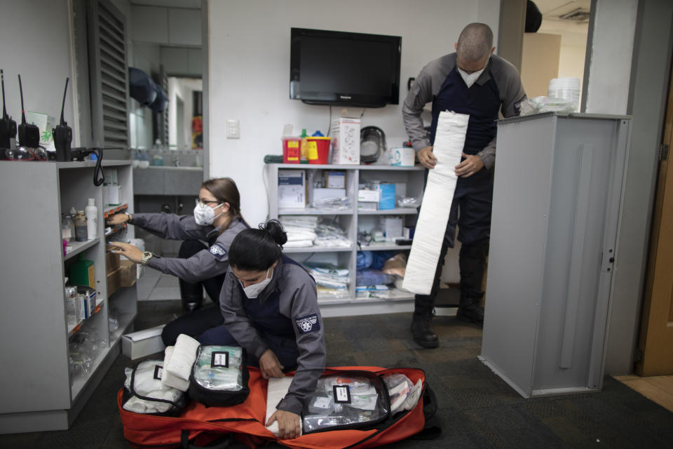 Wearing masks as a precaution against the new coronavirus, Angels of the Road volunteer paramedics, Laura Lara, from left, Zully Rodiz and Jonathan Quantip, resupply their trauma kit, in Caracas, Venezuela, Monday, Feb. 8, 2021. These self-sufficient volunteers seek their own funding and operate entirely independent of government. (AP Photo/Ariana Cubillos)