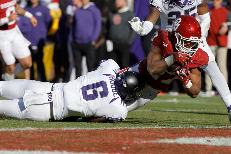 Oklahoma Sooners running back Gavin Sawchuk (27) dives for a touchdown over TCU Horned Frogs linebacker Jamoi Hodge (6) during a college football game between the University of Oklahoma Sooners (OU) and the TCU Horned Frogs at Gaylord Family-Oklahoma Memorial Stadium in Norman, Okla., Friday, Nov. 24, 2023. Oklahoma won 69-45.