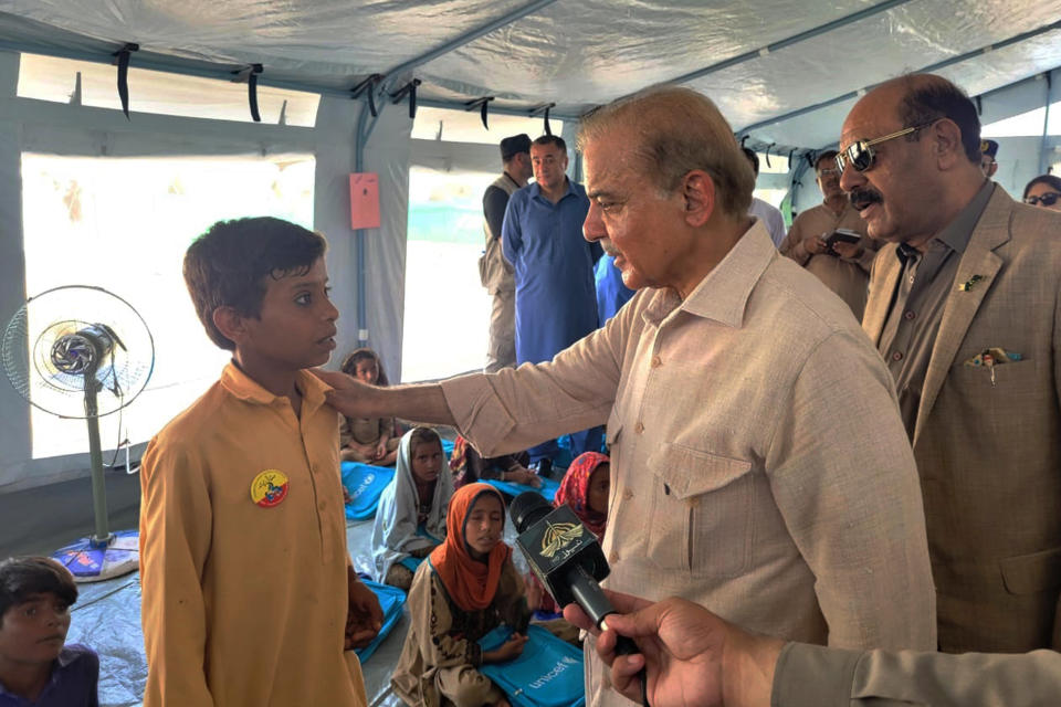 In this handout photo released by Press Information Department, Prime Minister Shahbaz Sharif, second right, talks a student at a makeshift school inside a tent in the flood-hit area of Suhbatpur in Baluchistan, Pakistan. Sharif on Wednesday promised the country's millions of homeless people that the government will ensure they are paid to rebuild their homes and return to their lives after the country's worst-ever floods. (Press Information Department via AP)